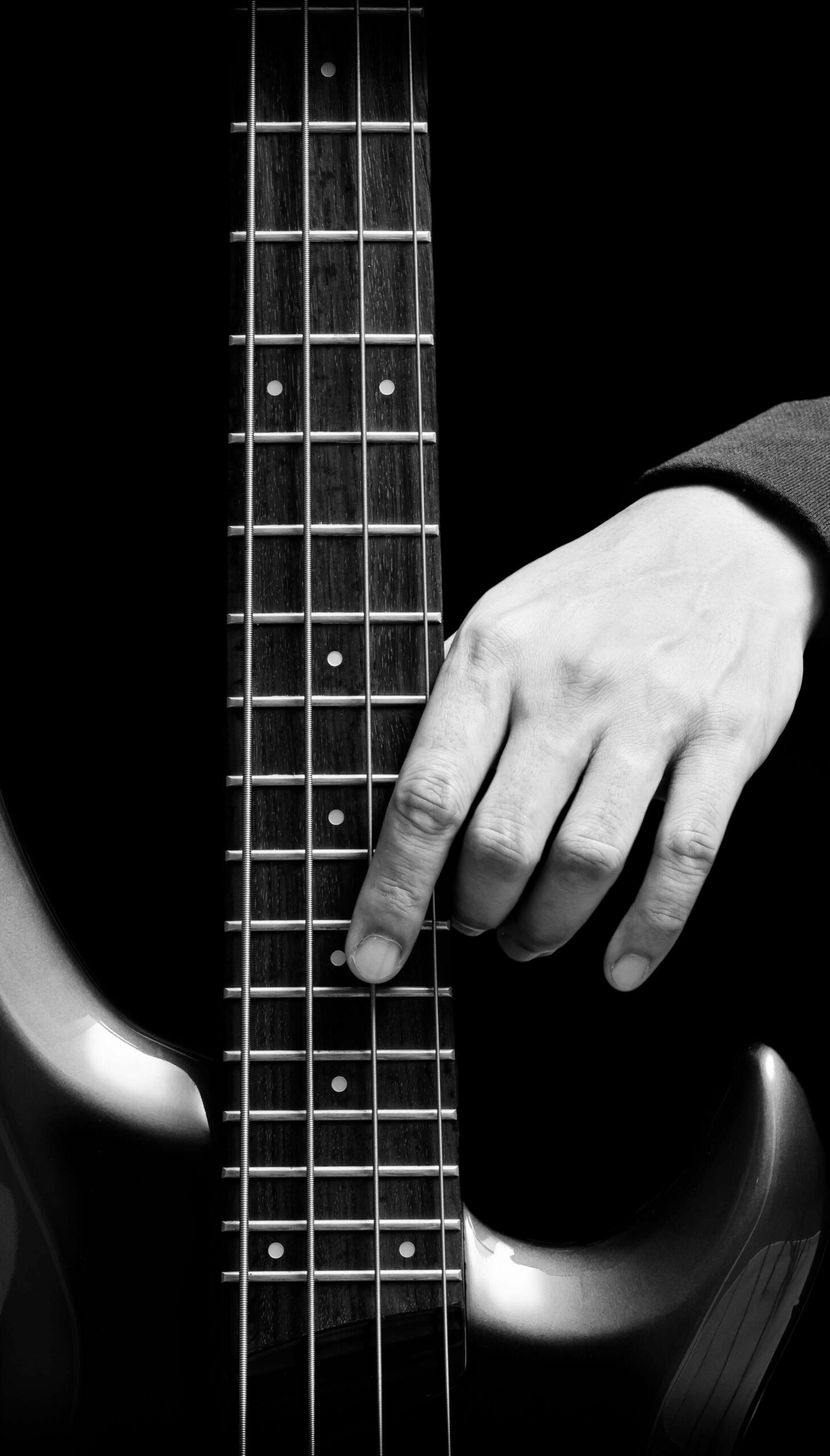 Hand eines Bassisten hat Kontakt zum Griffbrett eines 4-saitigen E-Basses